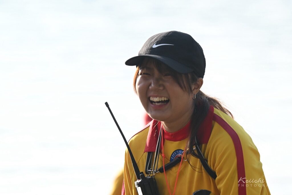 海水浴場で、無線機を身につけて笑顔を見せるライフセーバー
