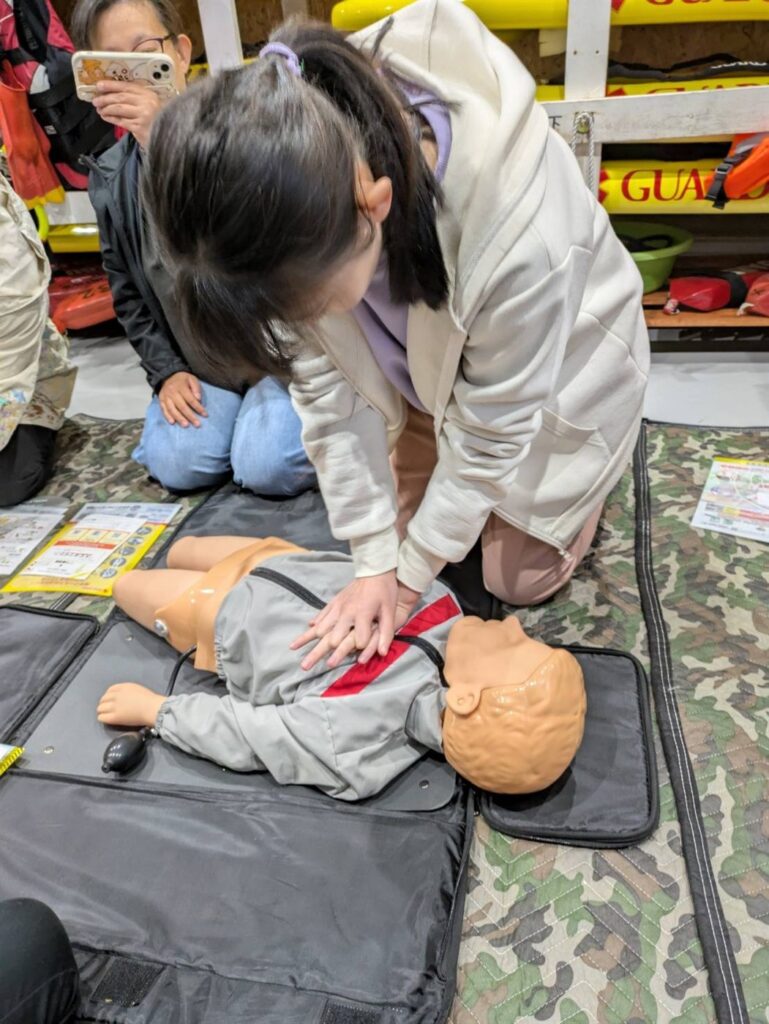 小児用の訓練人形を使って胸骨圧迫を練習する、小児・乳児の救命講習の受講者