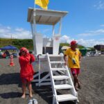 厚田海浜プールの監視台で、双眼鏡で水面を監視するライフセーバーと無線を持つライフセーバー
